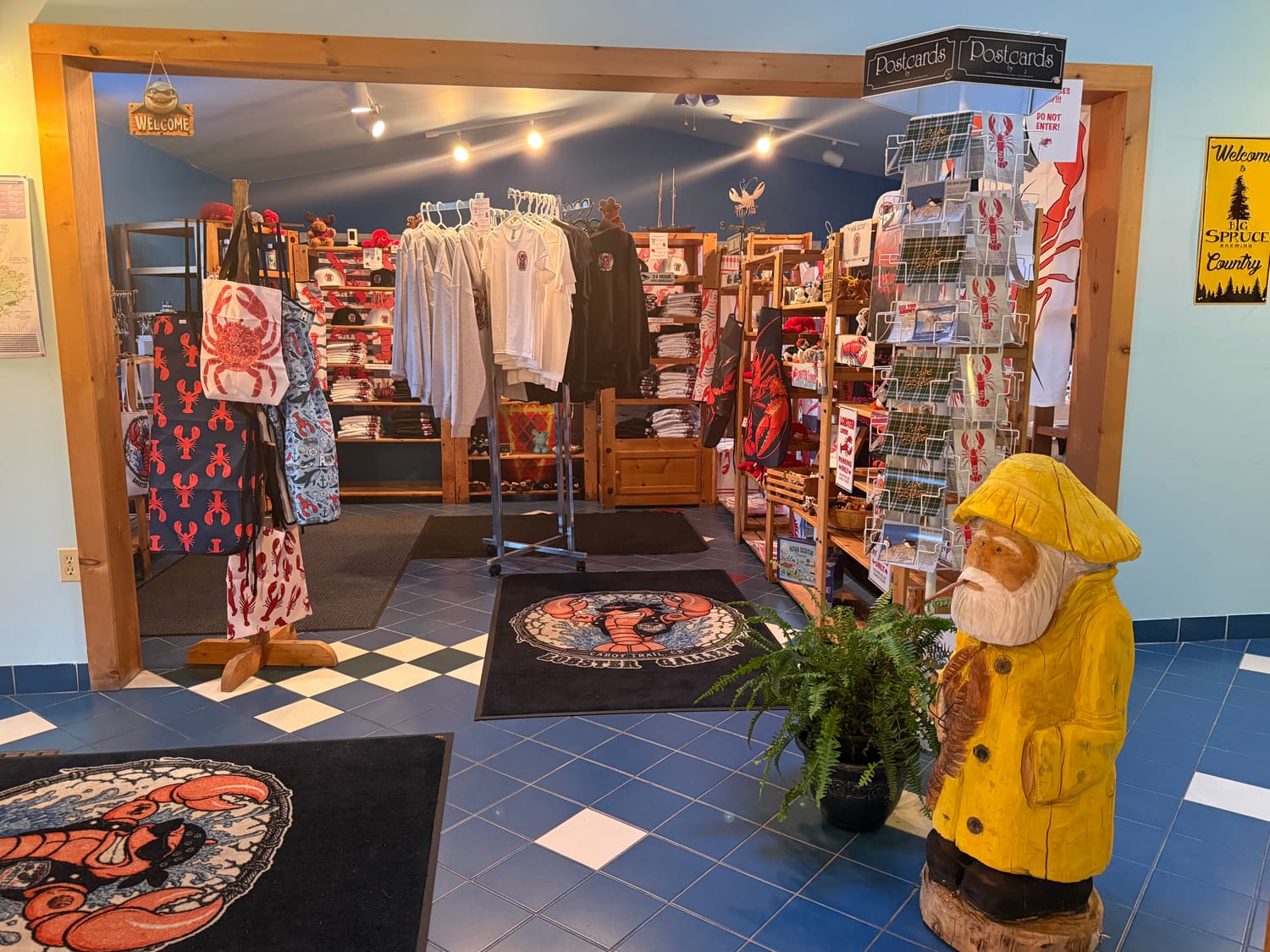 The gift shop entrance, with racks of shirts, postcards and a carved fisherman in a yellow raincoat