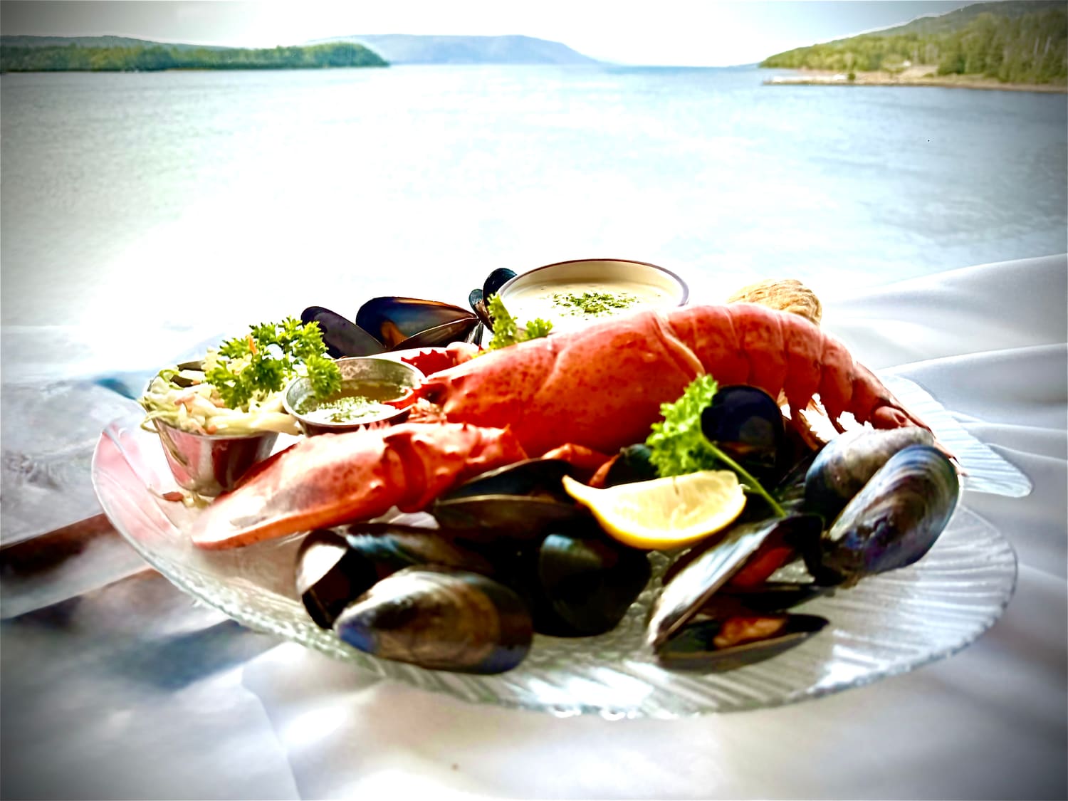 A lobster and mussels platter on a window table overlooking St. Ann's Bay