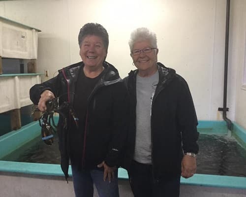Two of the team at the lobster pound holding a lobster